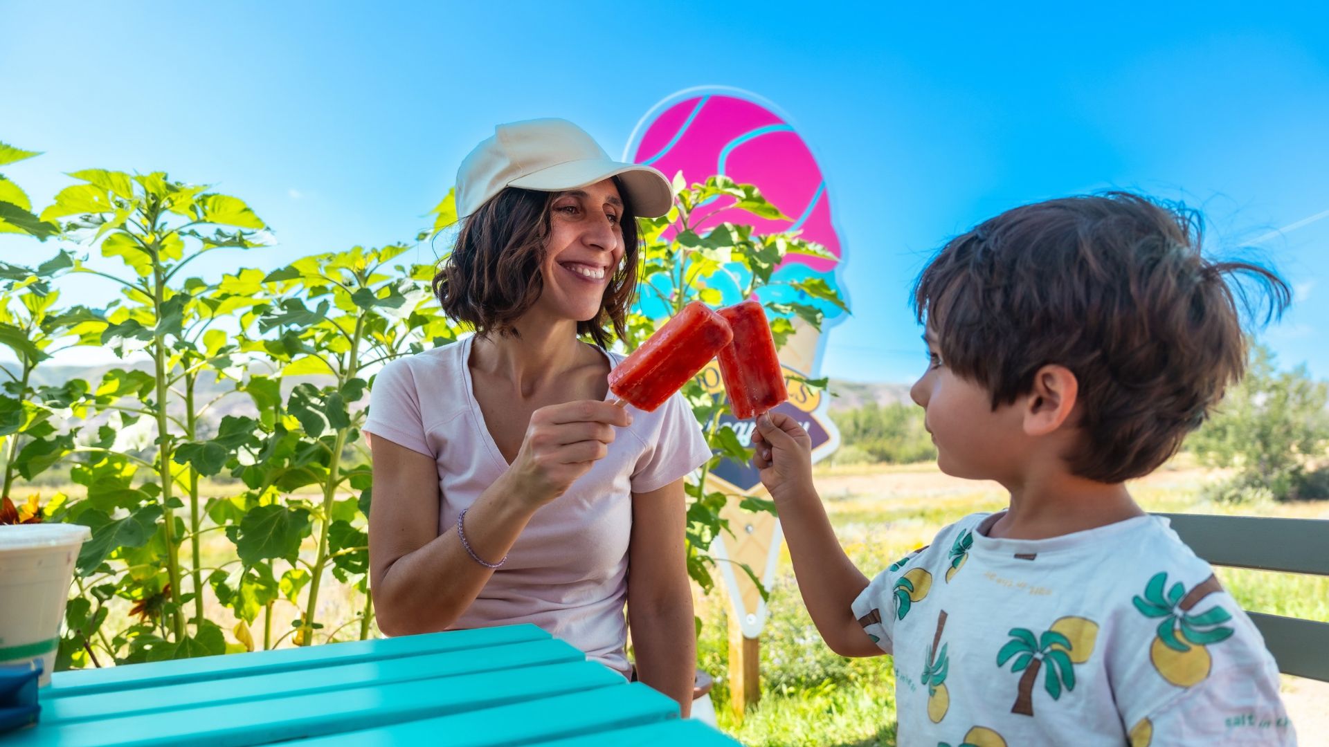 Mother and son are enjoying colorful popsicles at a picnic