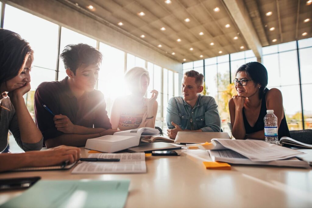 Young professionals collaborating on a research project around a meeting table.