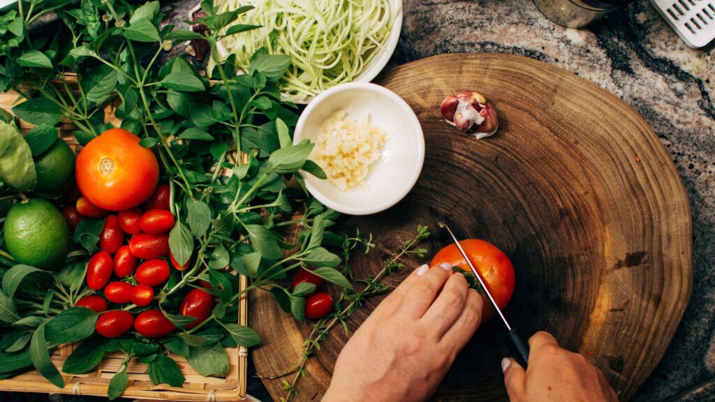 Tomato being sliced on a wooden board for an organic salad recipe