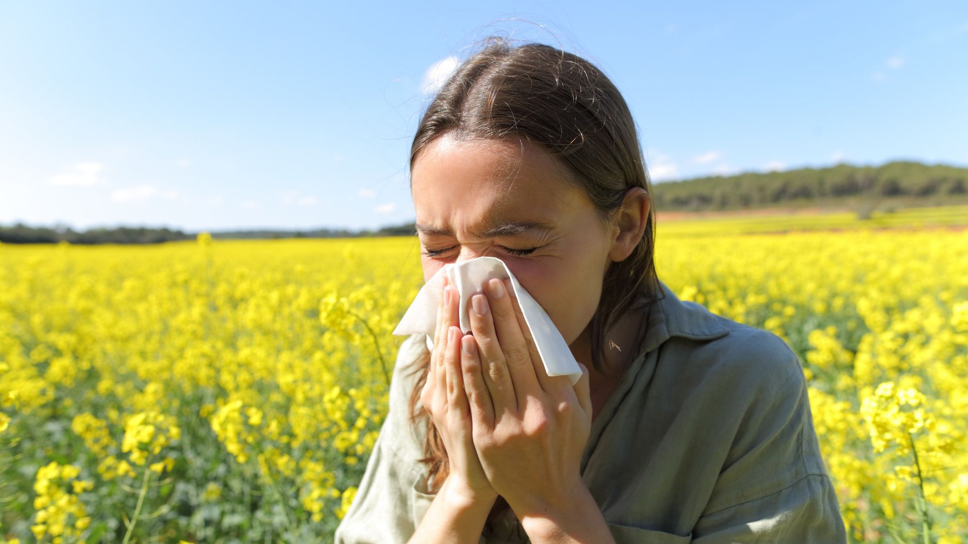 Woman suffering allergy coughing in a yellow flowered field