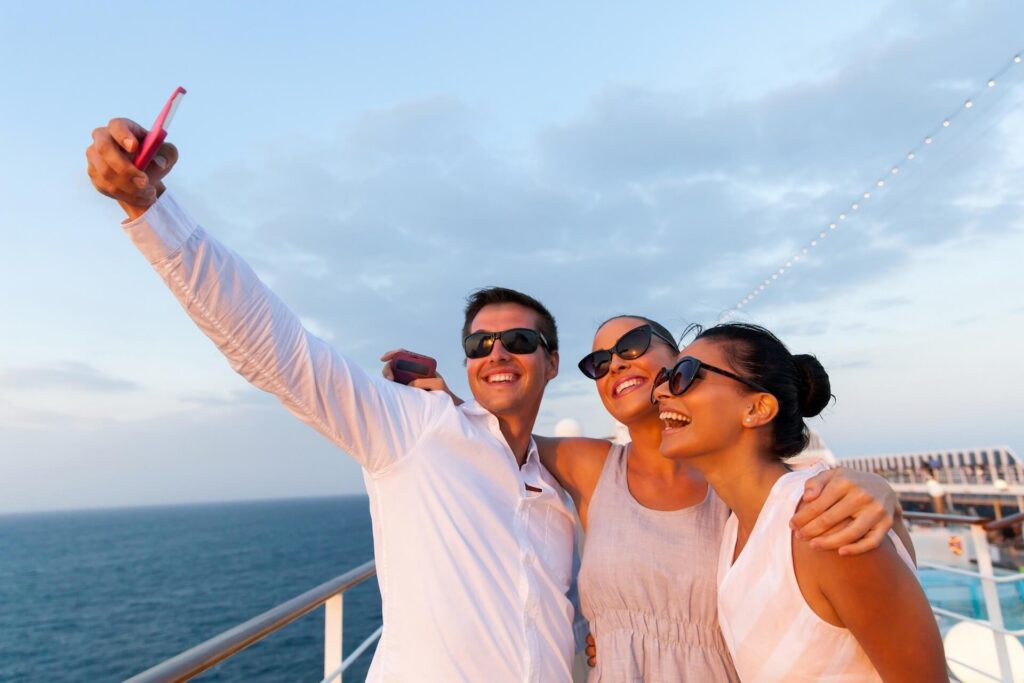 Three friends taking a selfie on a cruise ship at sunset.