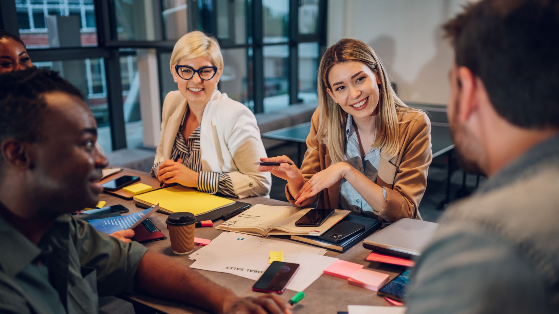 Happy multiracial business team working together at corporate briefing gathered at table in the conference room. Smiling diverse colleagues in a boardroom discussing business together.