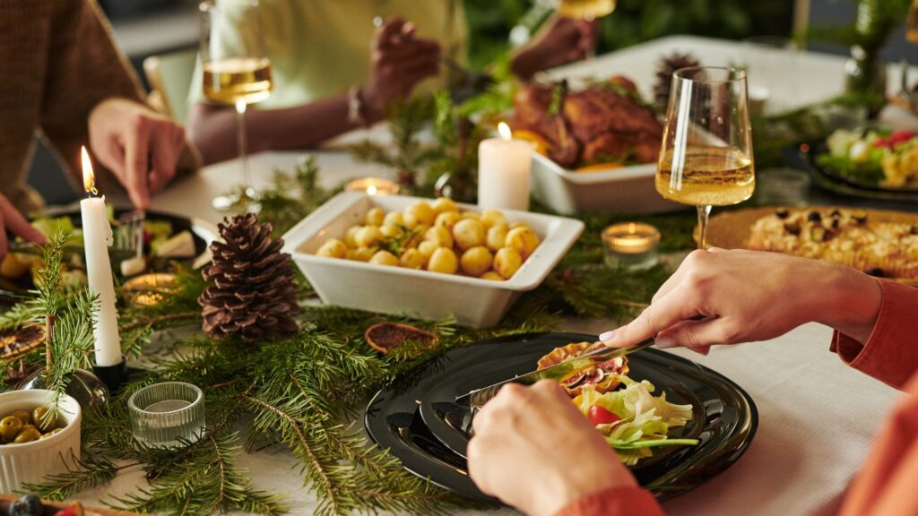 Caucasian woman eating Christmas meal with multiethnic group, hands visible