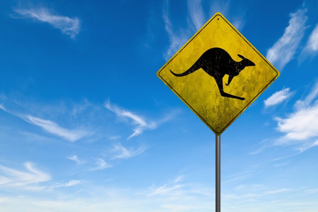 Yellow kangaroo crossing road sign against a bright blue sky.