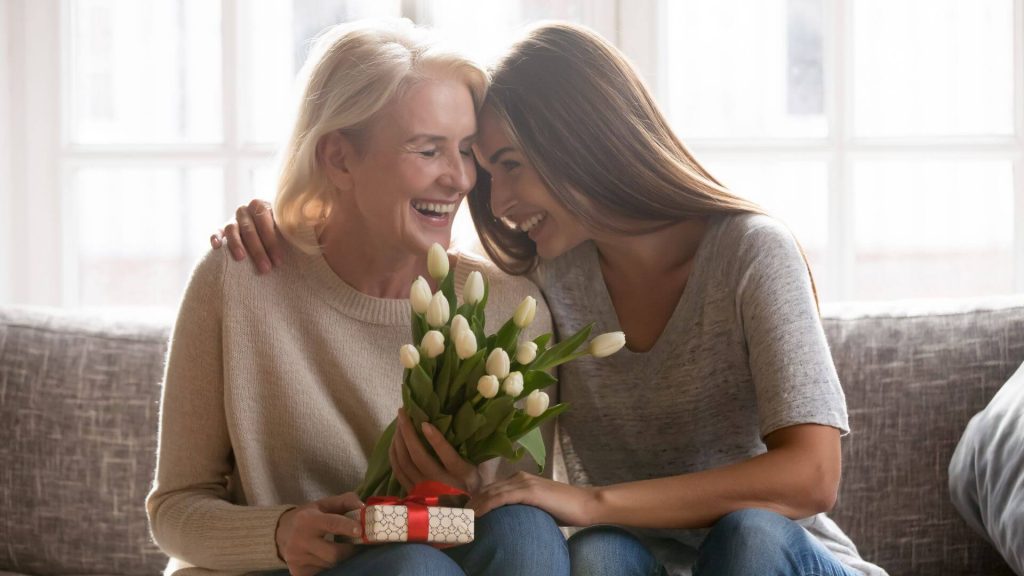 Mother and daughter sharing a gift and flowers.
