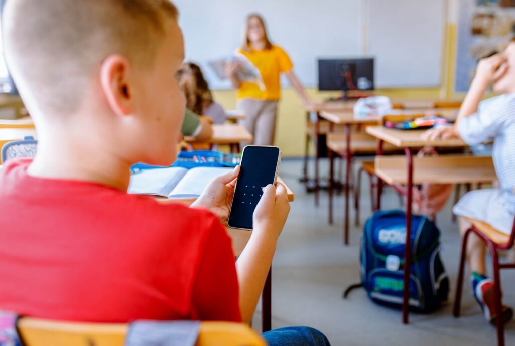 Boy using smart phone during primary school class.