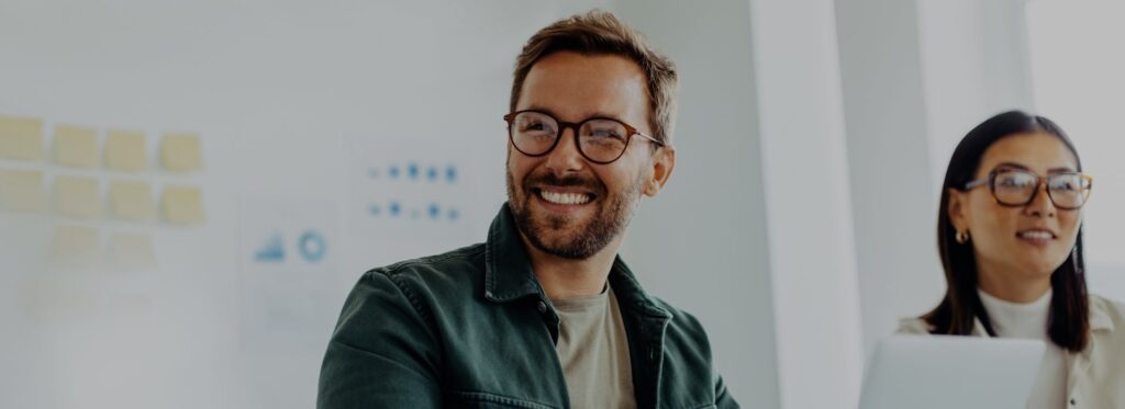 Happy business man listening to a discussion in an office boardroom. Business professional sitting in a meeting with his colleagues.