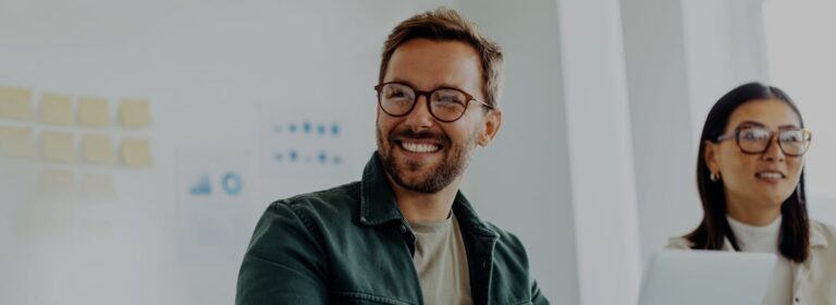 Happy business man listening to a discussion in an office boardroom. Business professional sitting in a meeting with his colleagues.