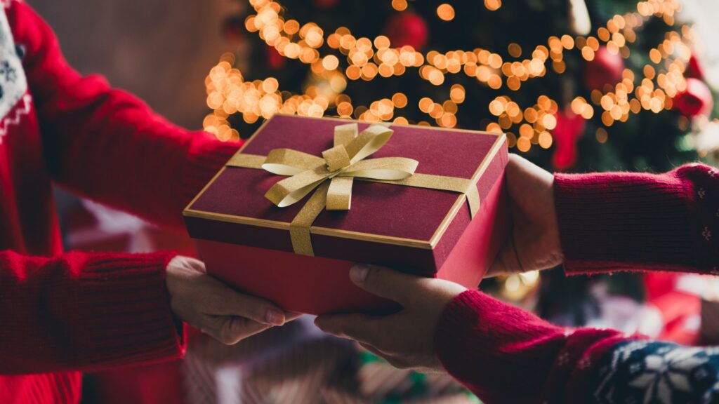 Cropped photo of two people arms hold exchange giftbox christmas festive illumination apartment indoors