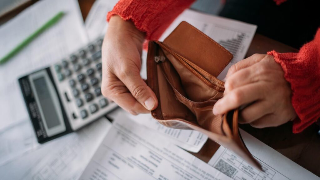 The hands of an elderly woman with an empty wallet and a lot of utility bills. Pensioner and payment of utilities for heating, electricity, gas