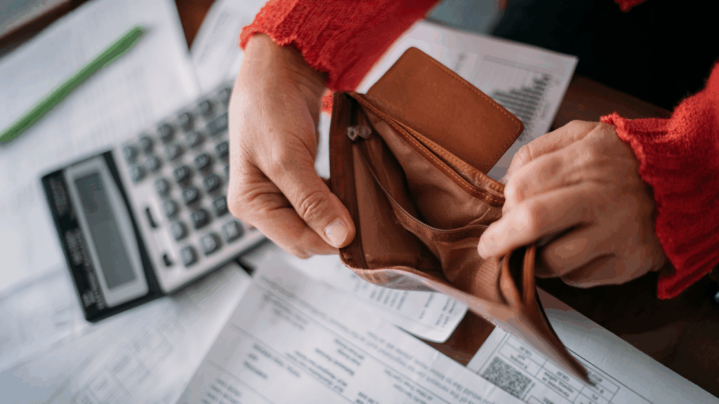 The hands of an elderly woman with an empty wallet and a lot of utility bills. Pensioner and payment of utilities for heating, electricity, gas