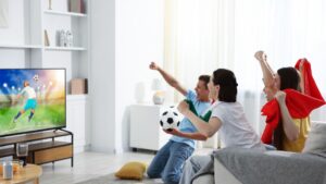 Football fans watching soccer match on TV set at home
