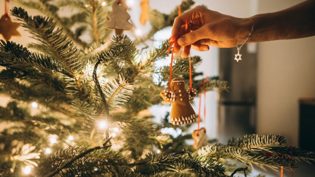 Female hand hangs angel gingerbread on the Christmas tree
