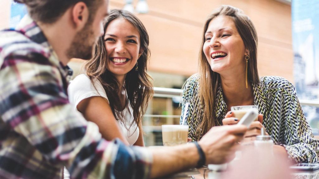 Three friends are laughing and chatting outdoors.