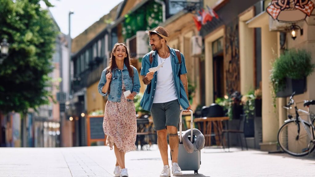 Happy couple of tourists walking in the city while traveling together.