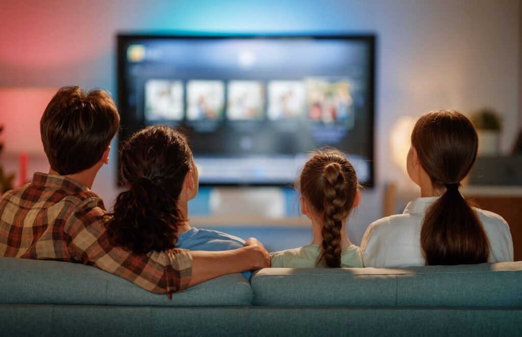 **Alt text:** Family sitting on a couch watching a streaming service on TV.