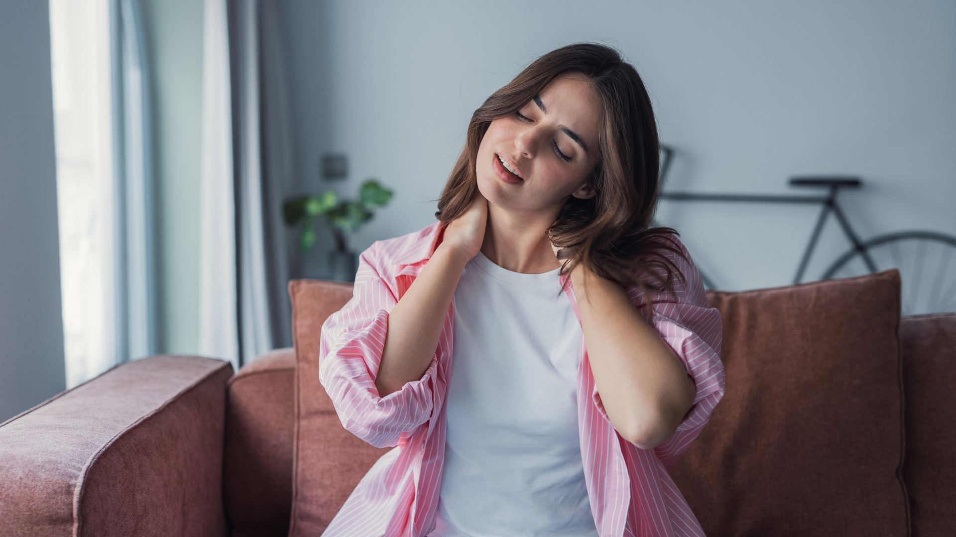 Tired young woman touch neck suffer from muscular spasms