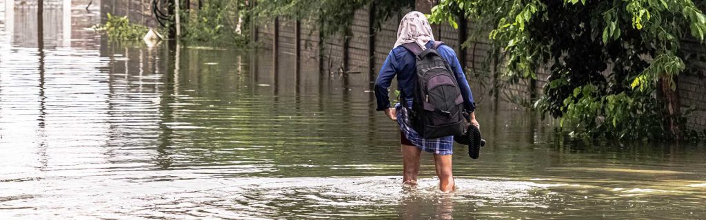 Woman wading through flood with backpack