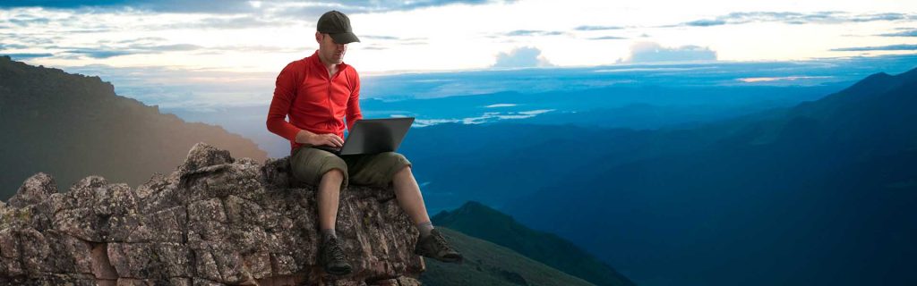 man remote working on a cliff edge