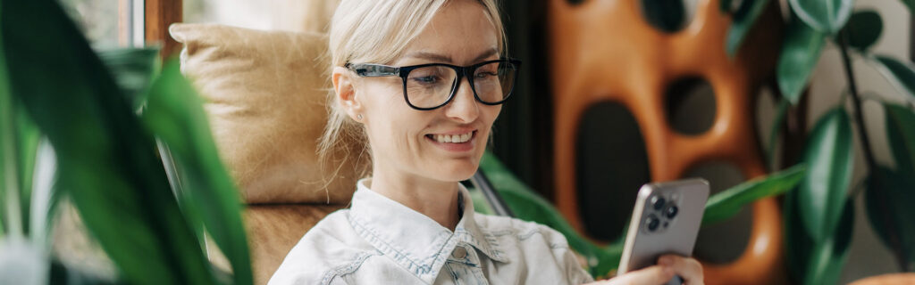woman wearing glasses reading her mobile screen