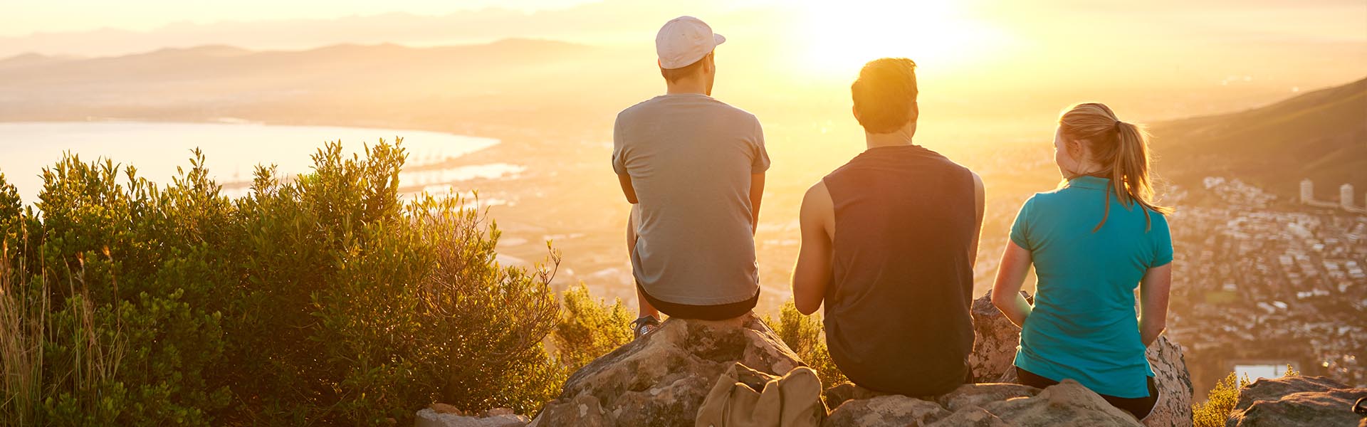 group of friends sitting at thew top of a mountain