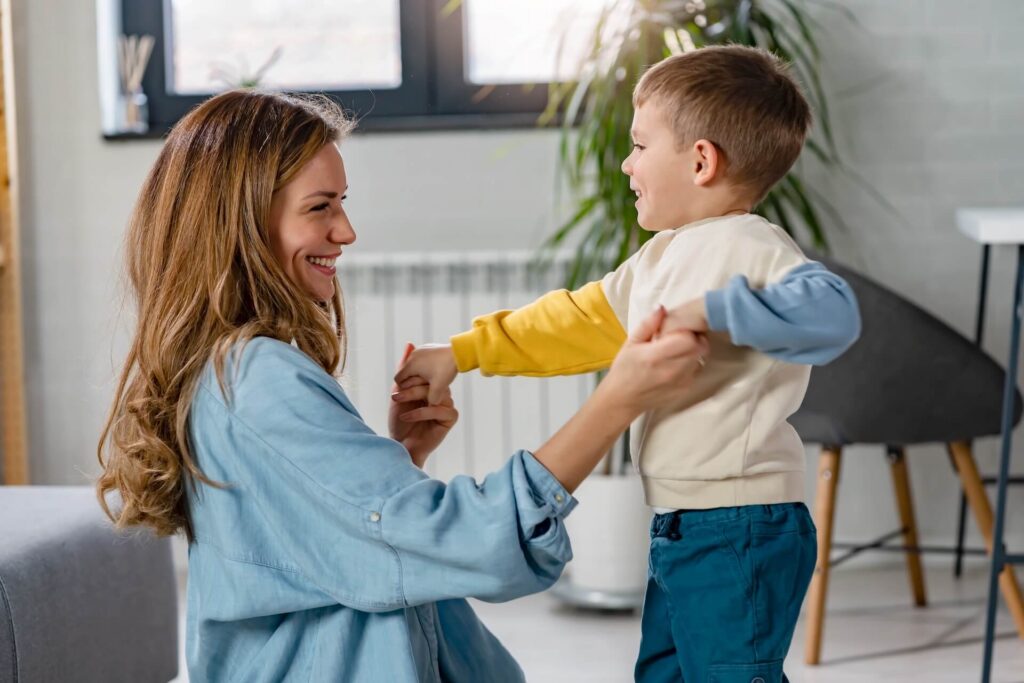 Cheerful mother and her cute little son playing at home, smiling. Togetherness.