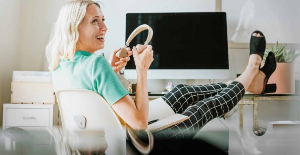 smiling woman sitting feet up holding headphone