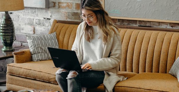 A woman working at a laptop sitting on a couch
