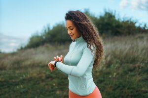 A fitness girl is looking at her smart watch to see how many steps she has been taking, as well as her pulse rate.