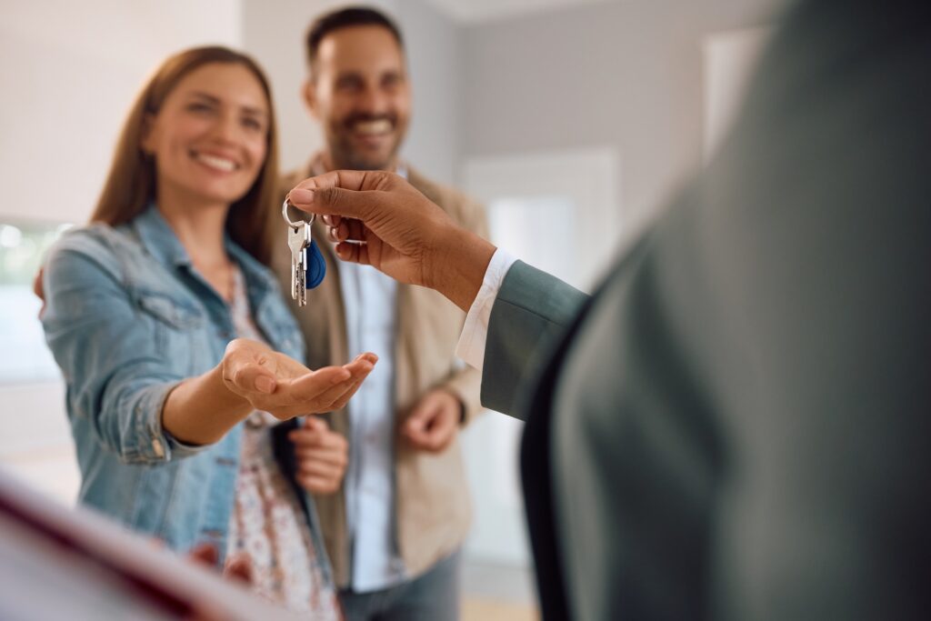 Close up of happy couple receiving keys of their new home from real estate agent
