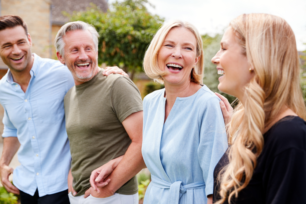 Family With Senior Parents And Adult Offspring Walking And Talking In Garden Together