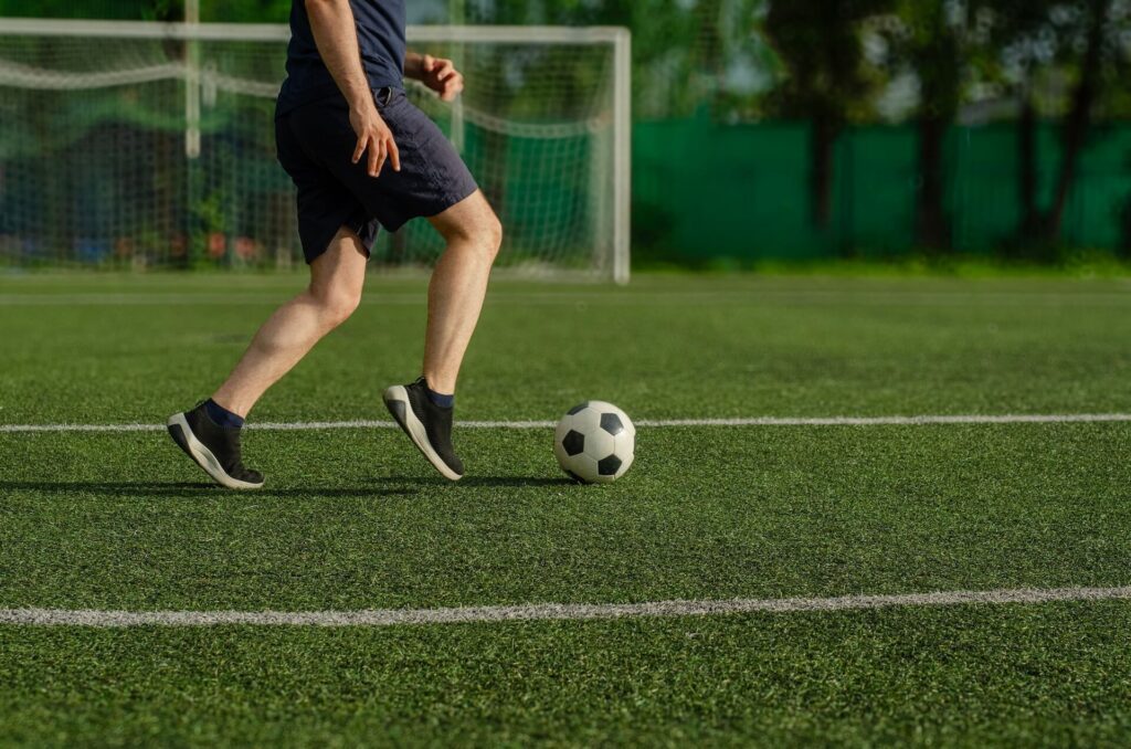 soccer player dribbles on soccer pitch